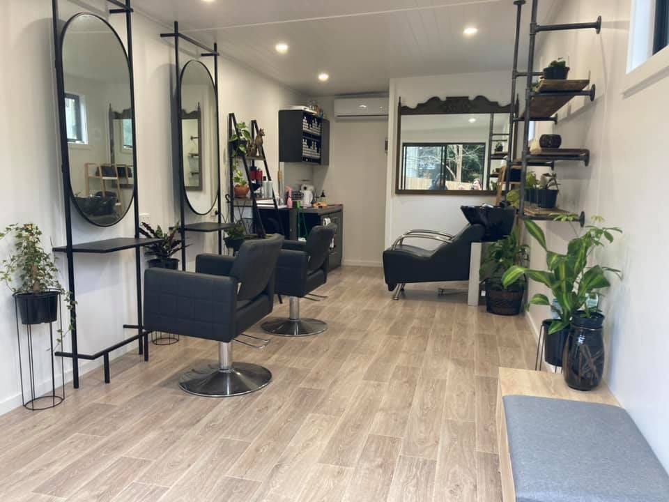 Modern hair salon interior with styling chairs, large mirrors, and wooden flooring